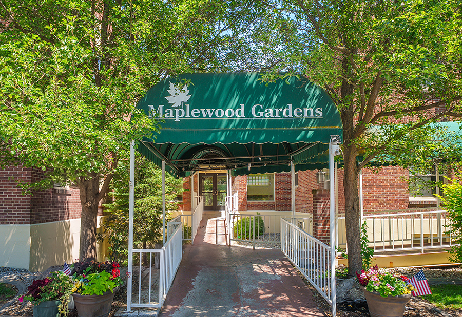Entrance to Maplewood Gardens with greenery and flowers.