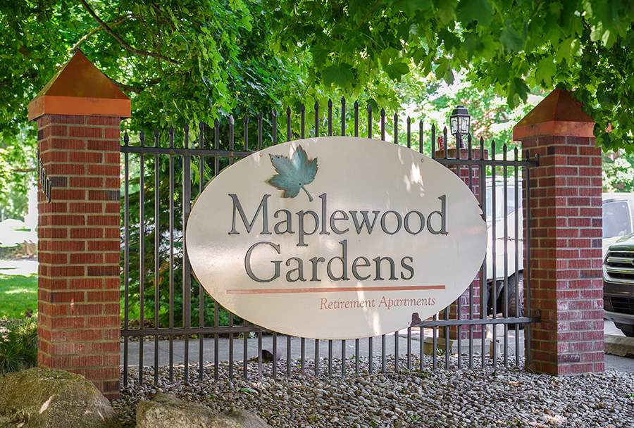 Sign for Maplewood Gardens Retirement Apartments surrounded by greenery.