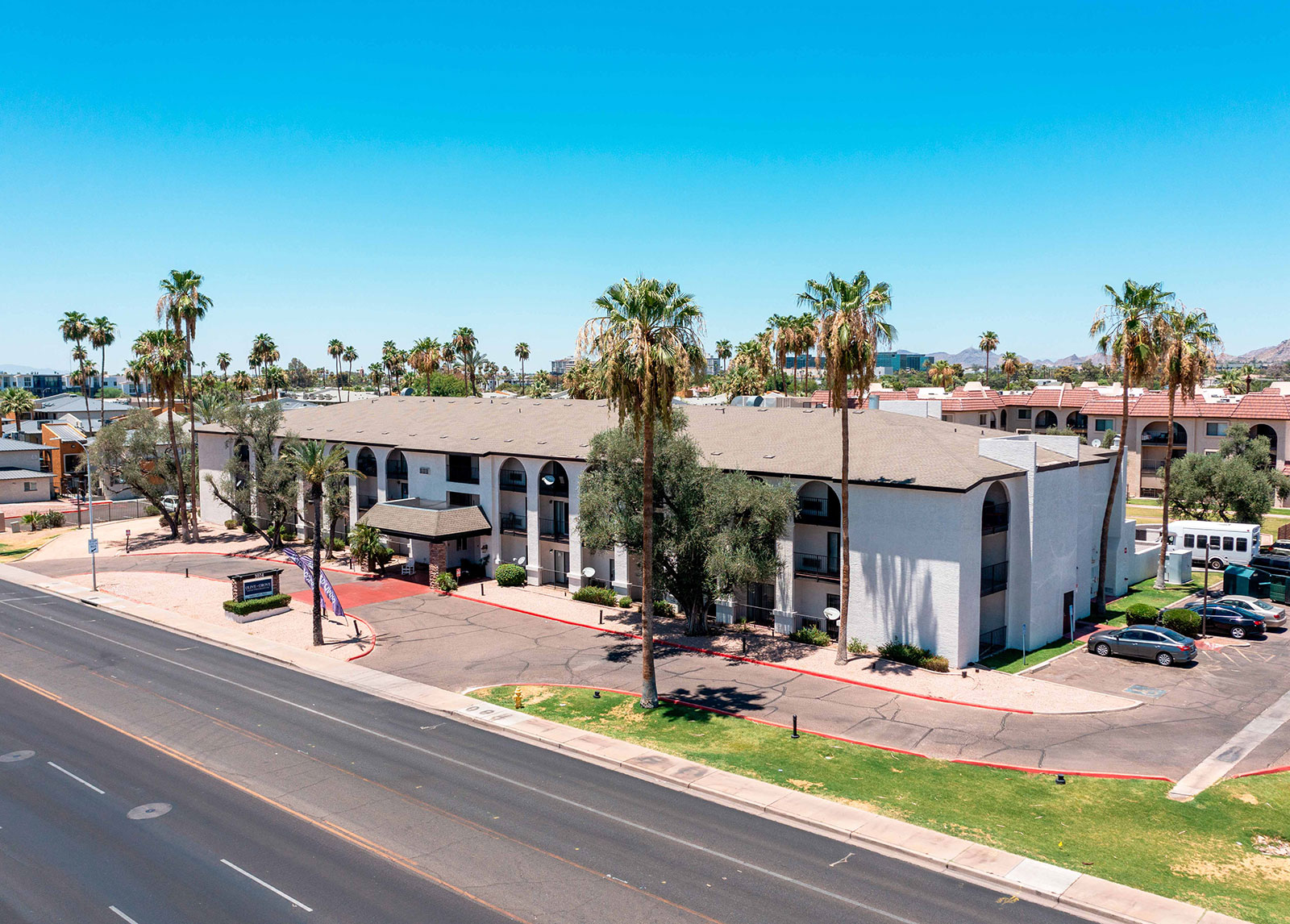 Aerial view of a hotel with palm trees and road.