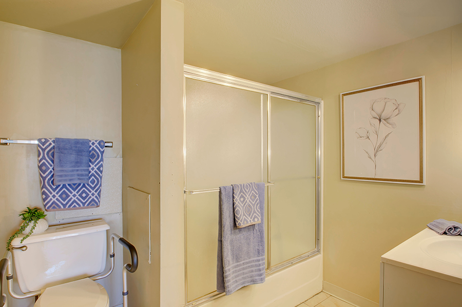 Modern bathroom with blue towels and floral artwork.