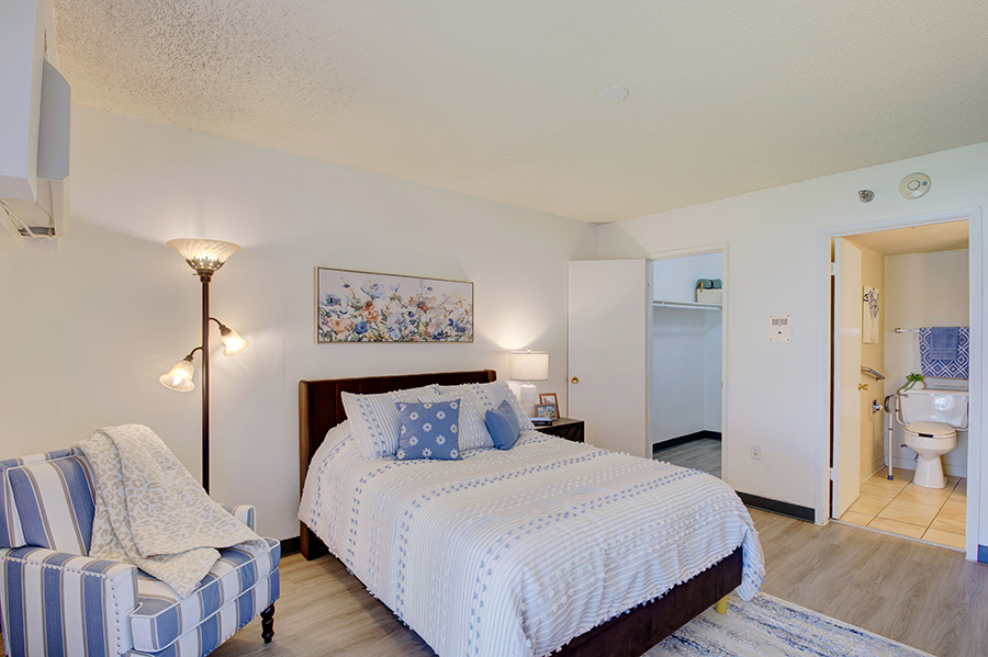 Cozy bedroom with bathroom, chair, and decorative elements.