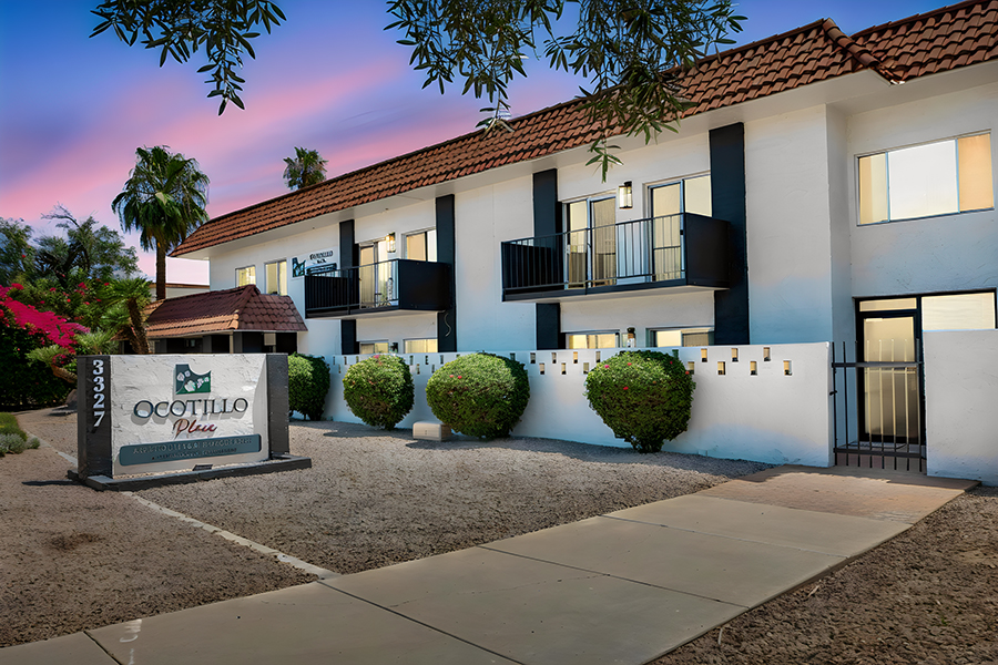 Two-story apartment building with landscaping and signage.