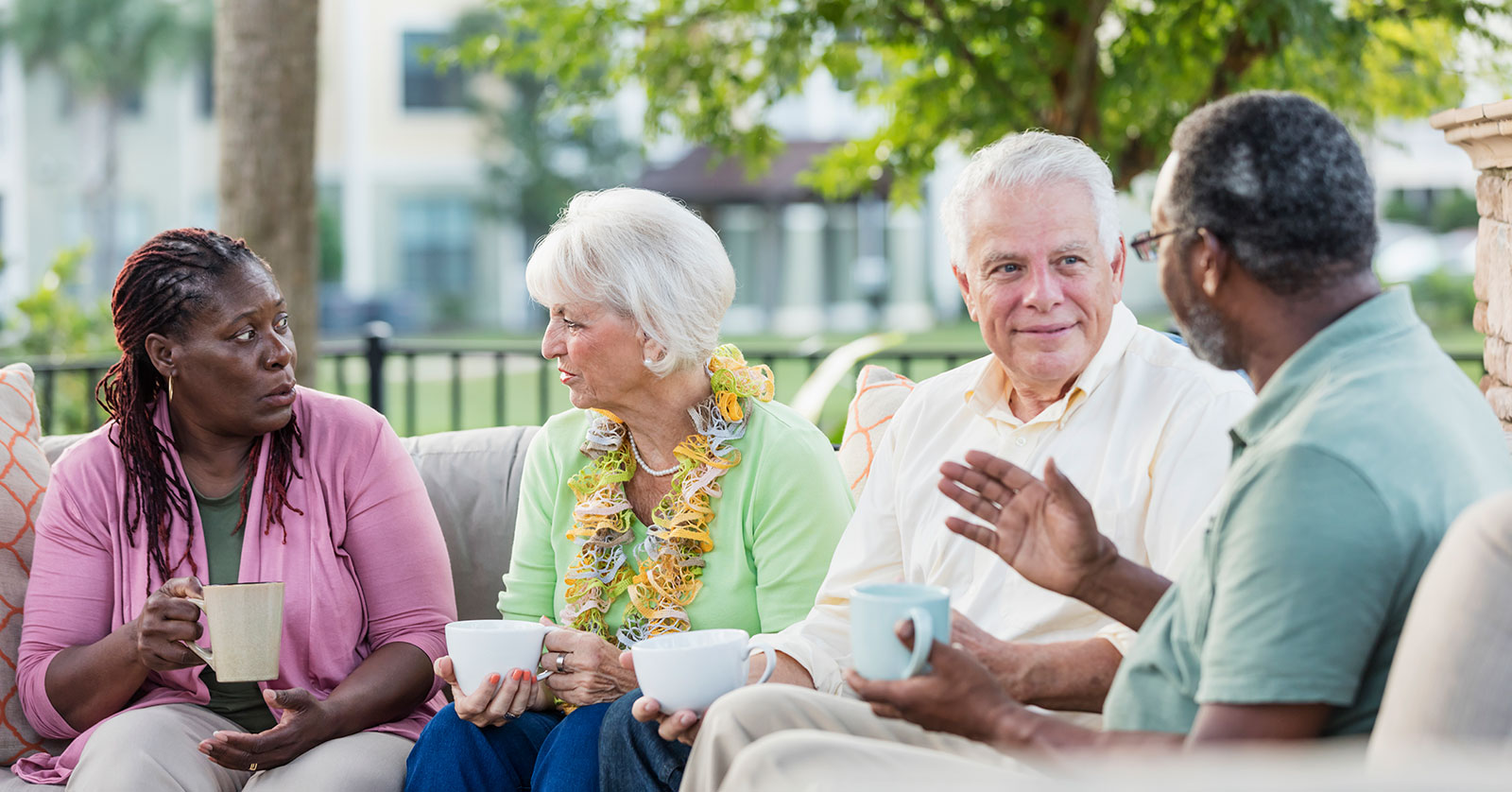 Four seniors enjoying conversation over drinks outdoors.