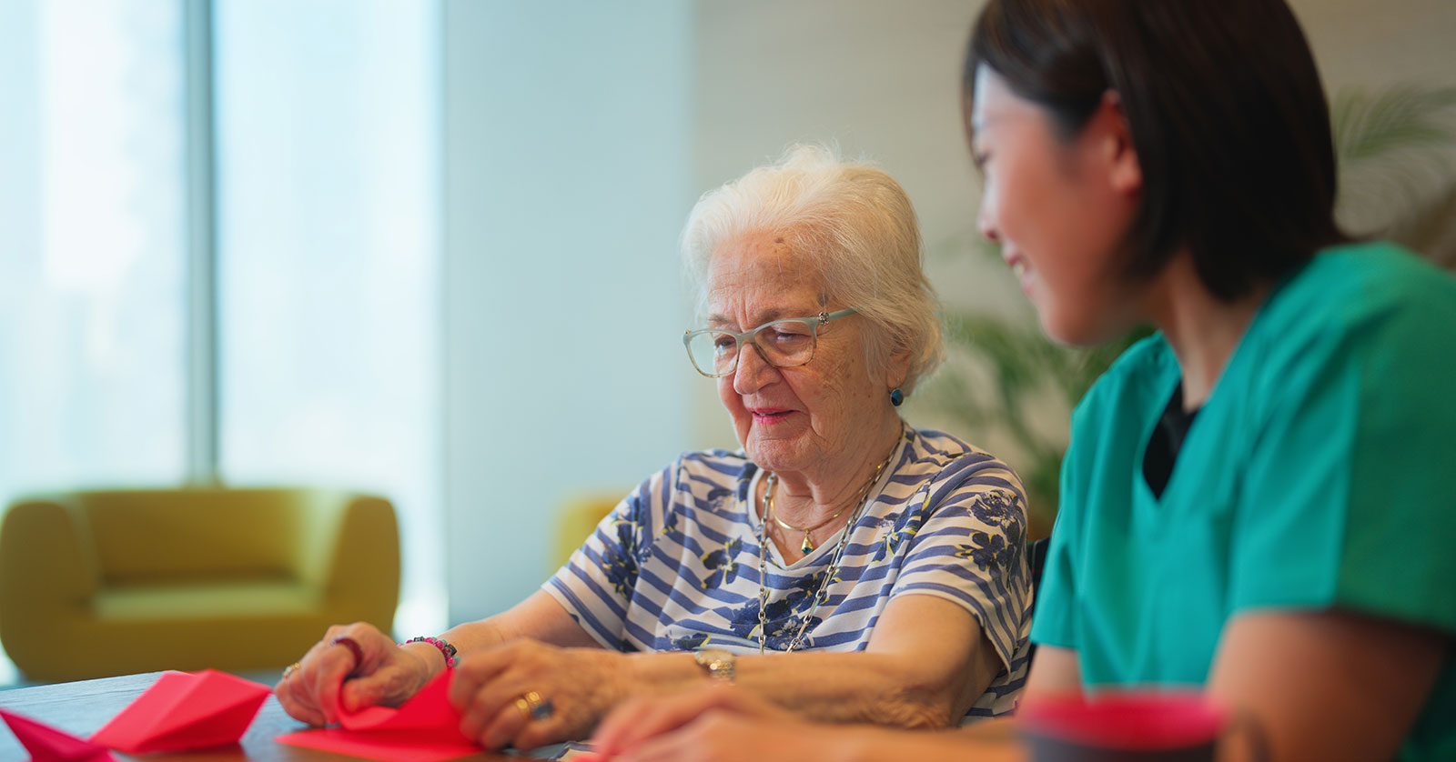 Two women engaged in paper folding activity together.