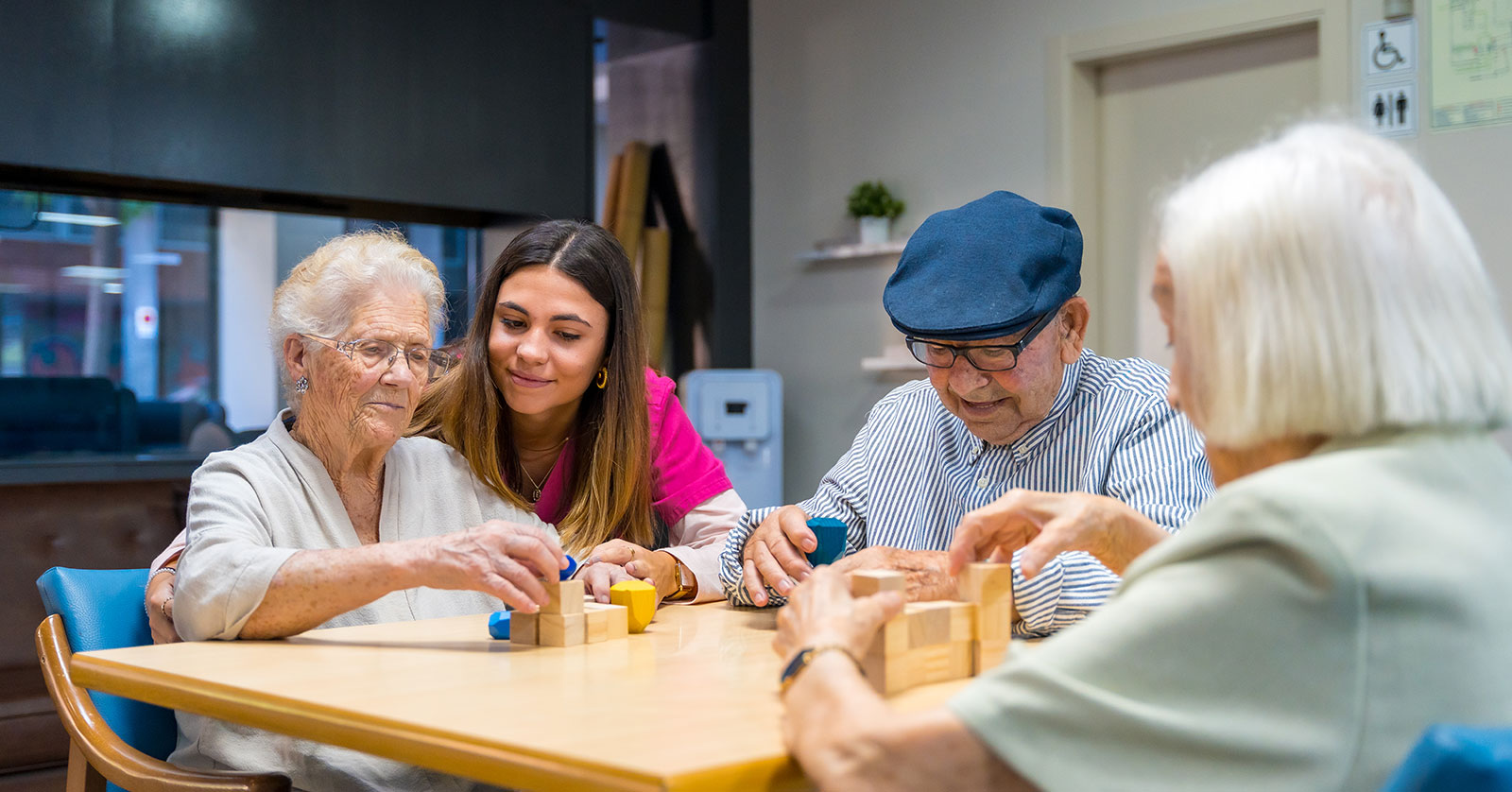 Seniors and caregiver engaging with colorful building blocks.