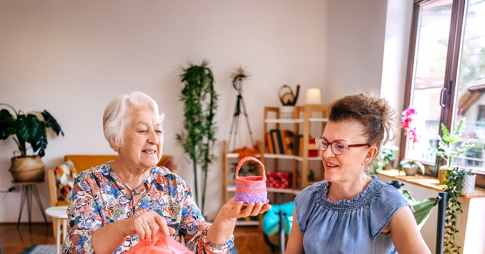 Two women crafting colorful crochet baskets together.