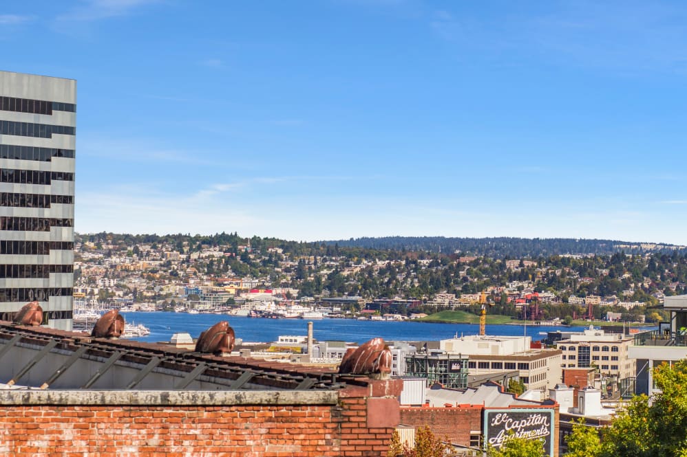 City skyline with water and distant hills under blue sky.