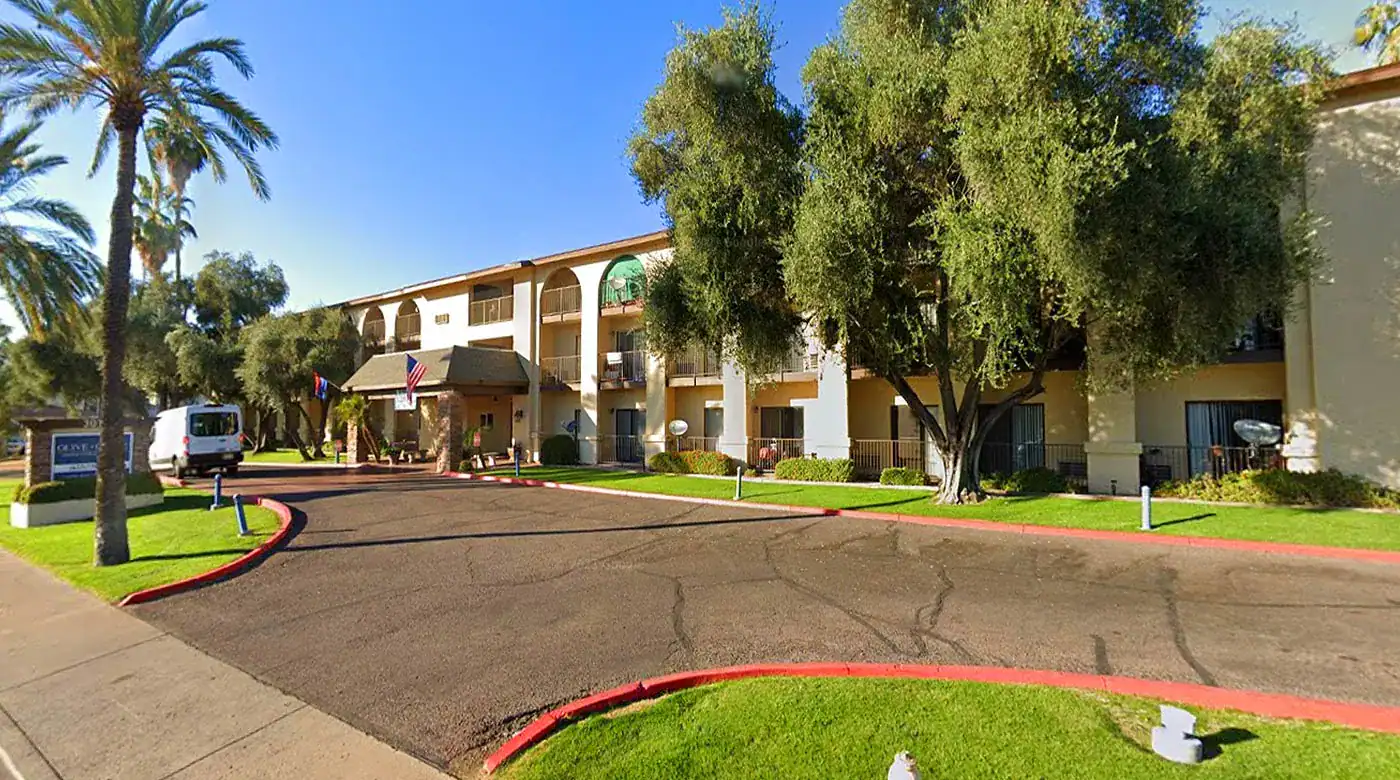 Hotel exterior with palm trees and clear blue sky.