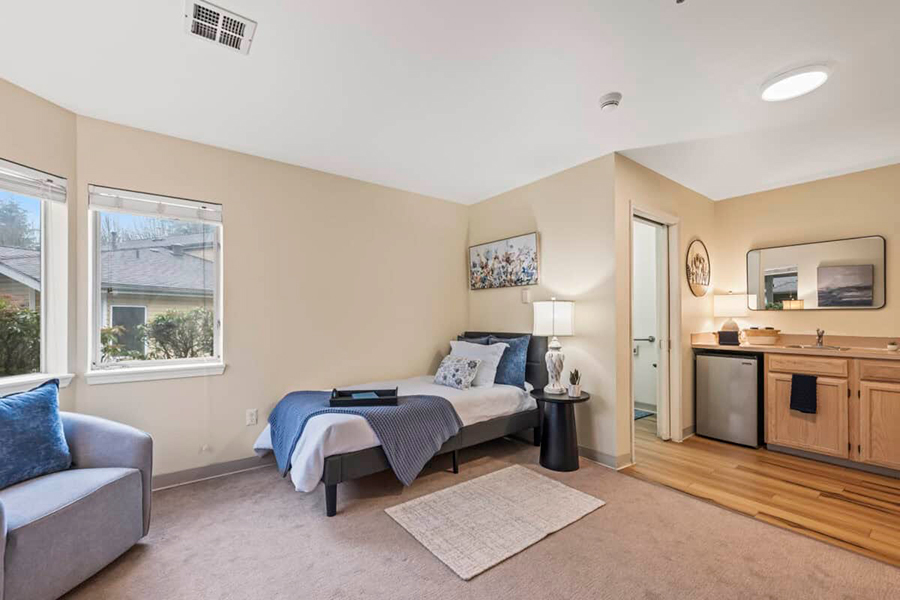 Cozy room with bed, kitchenette, and natural light.