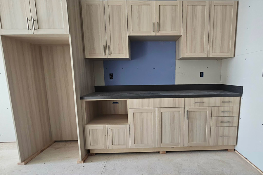 Modern kitchen cabinetry with light wood and black countertop.