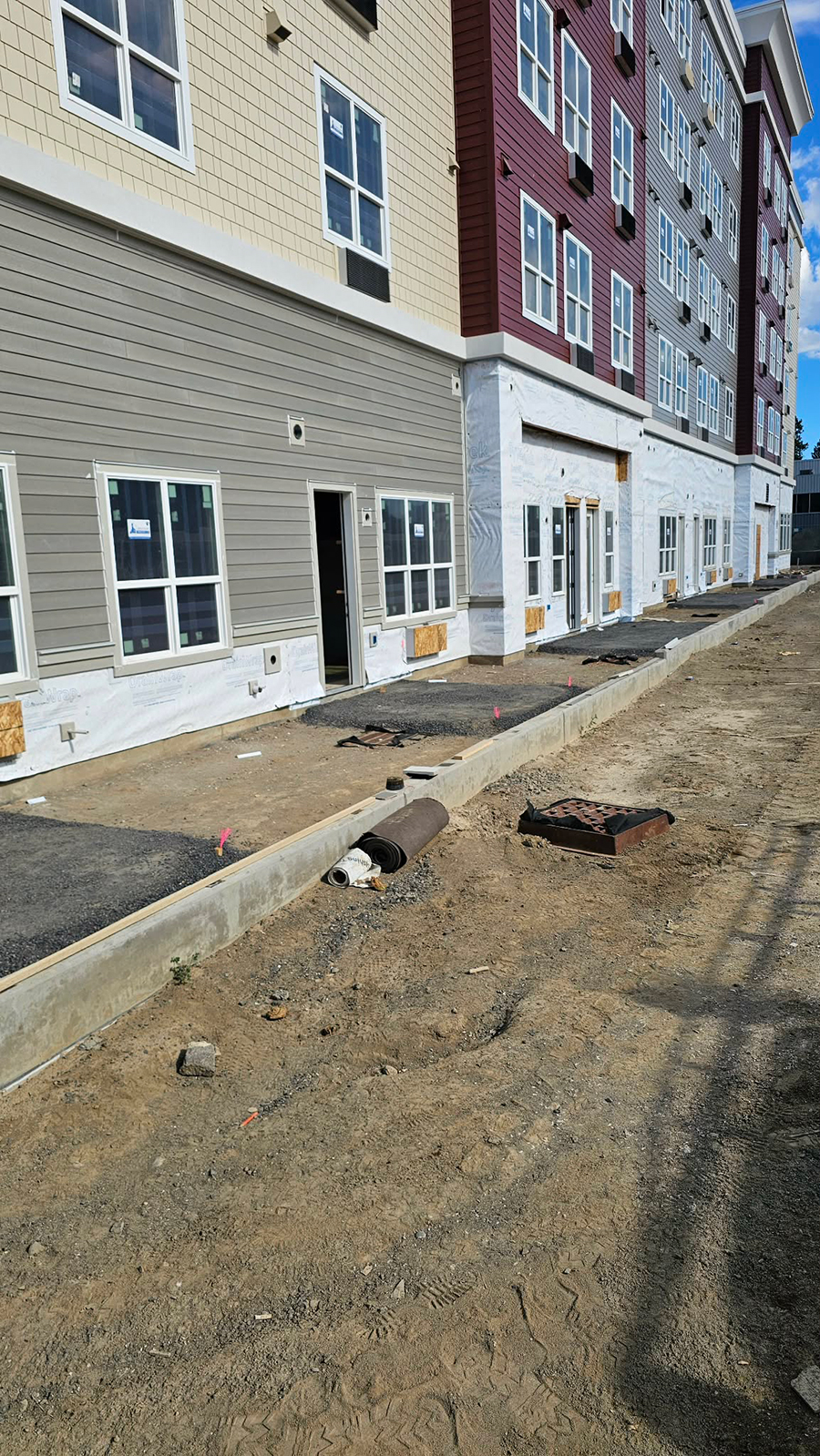 Construction site with multi-colored building and unfinished landscaping.