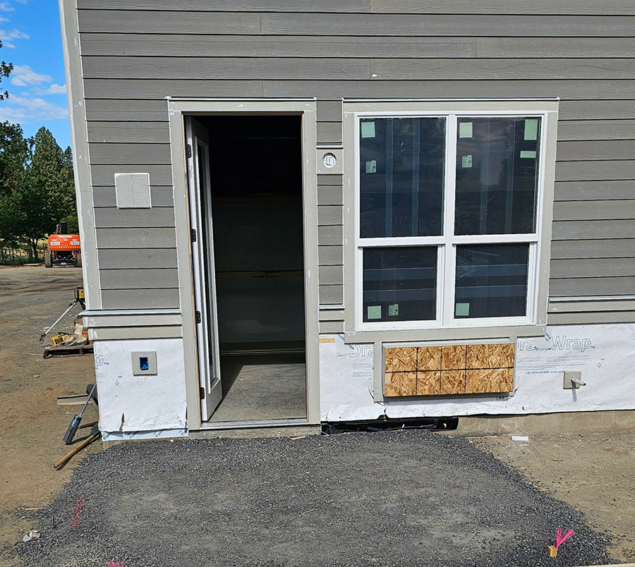 New construction with entrance and window, unfinished exterior.
