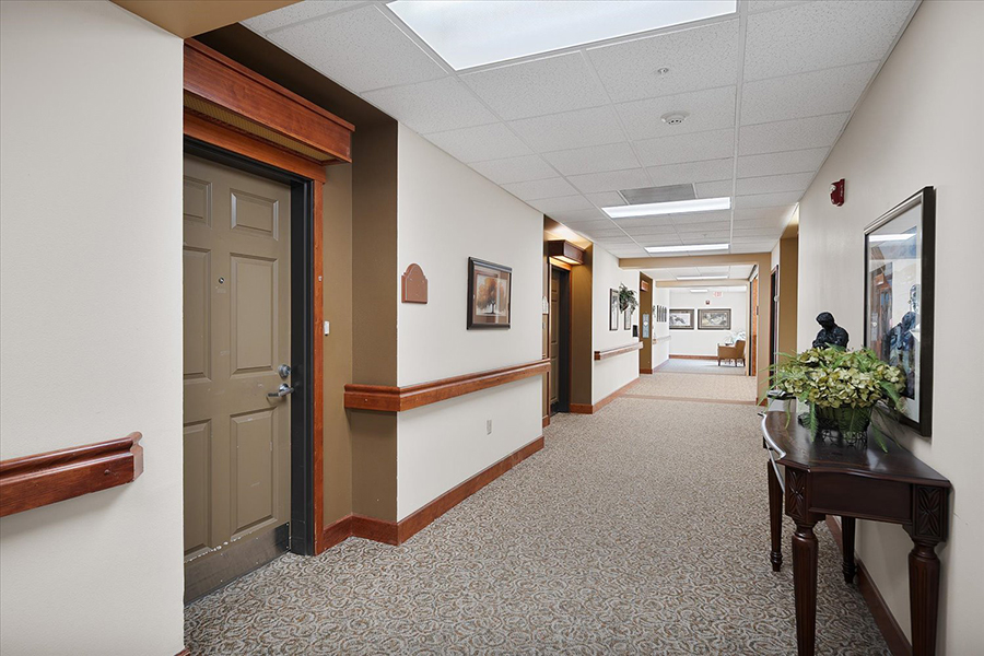 Long, well-lit hallway with door and decorative accents.