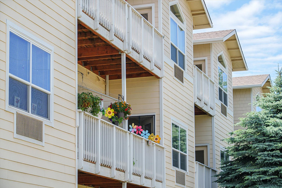 Two apartment balconies with colorful flowers and greenery.