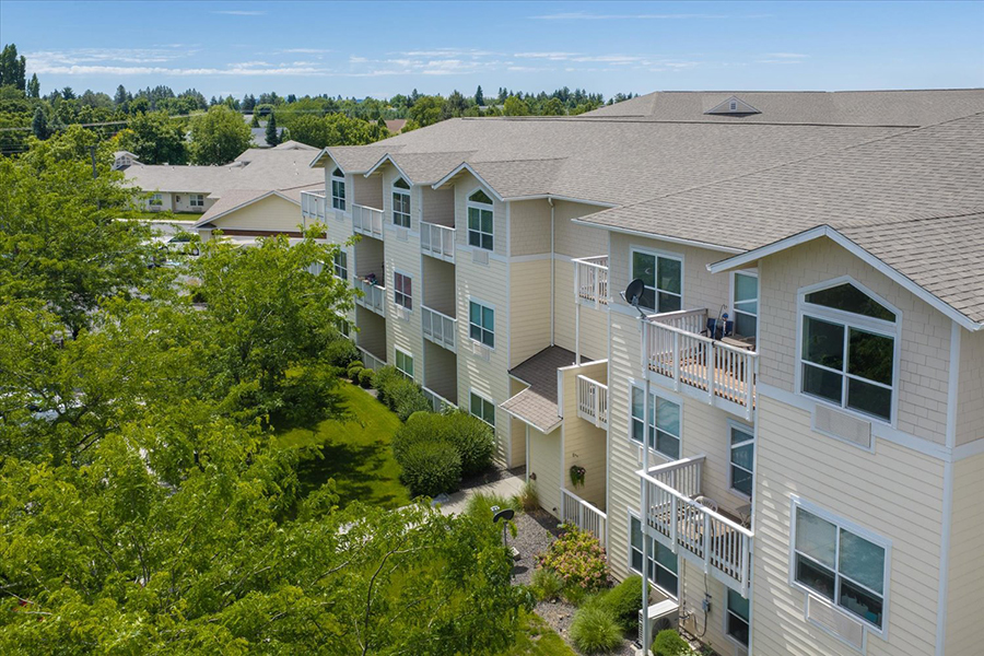 Multistory apartment building surrounded by greenery and blue sky.