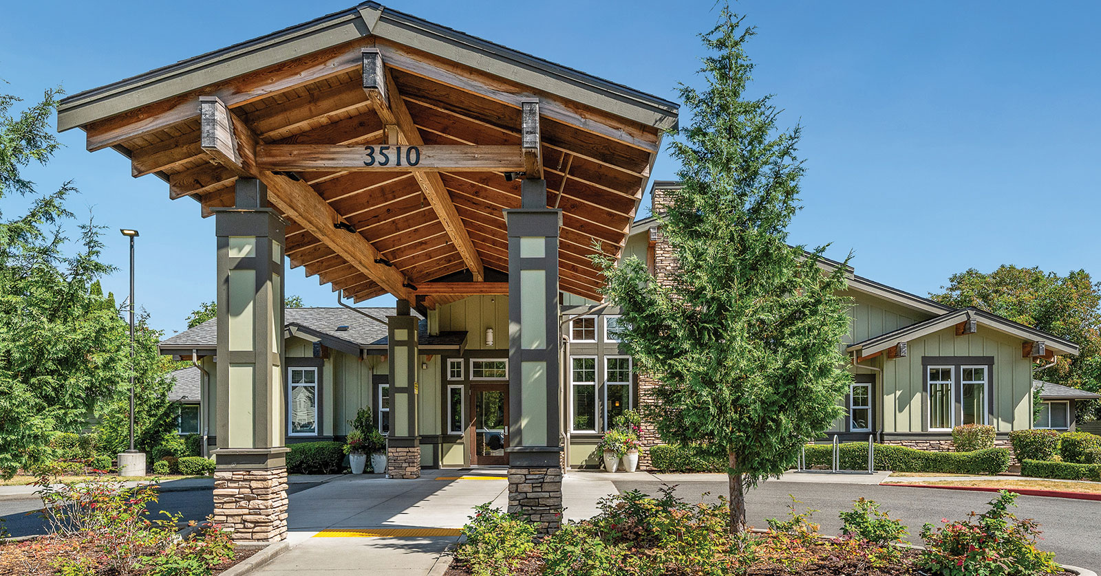 Modern building entrance with wooden awning and landscaping.