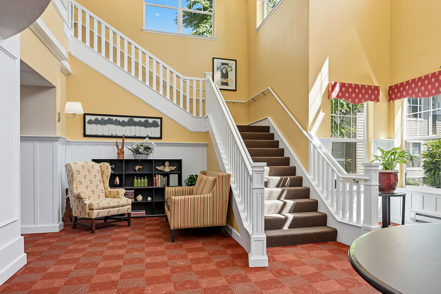 Bright foyer with staircase, seating, and large windows.