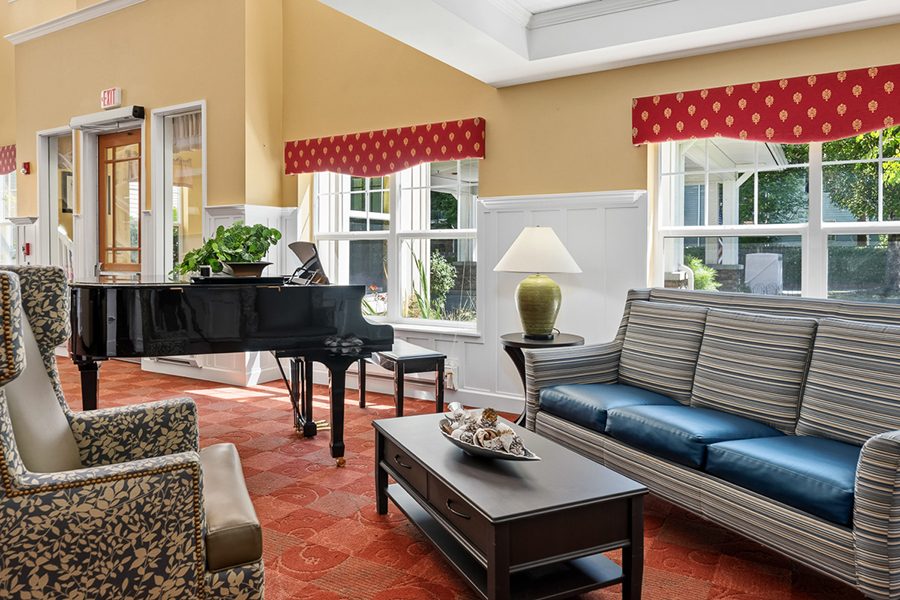 Cozy lounge area with piano, plants, and comfortable furniture.