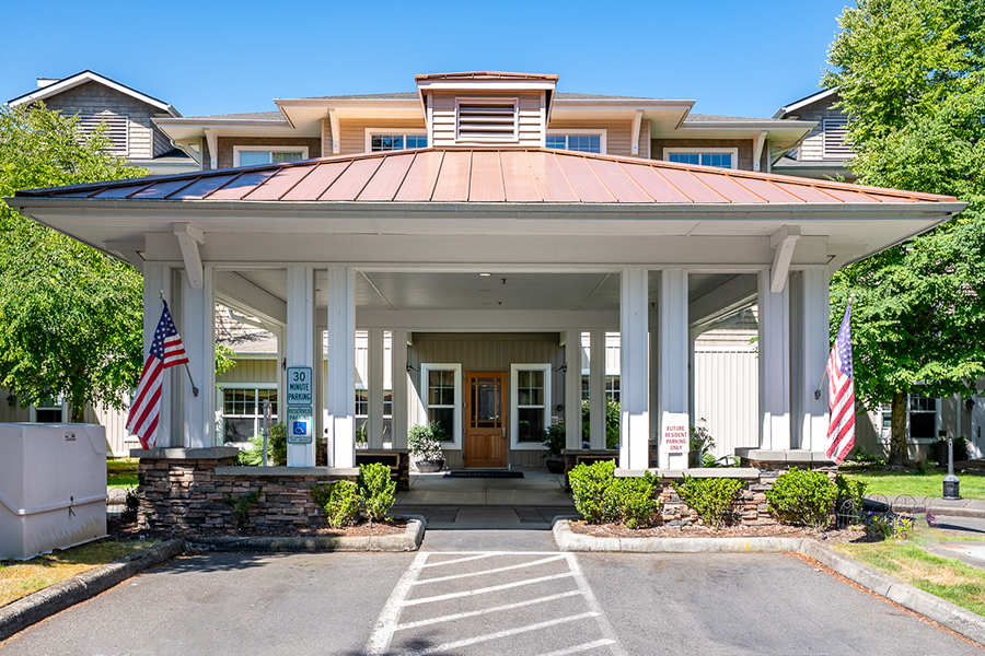 Entrance of a building with a covered porch and flags.