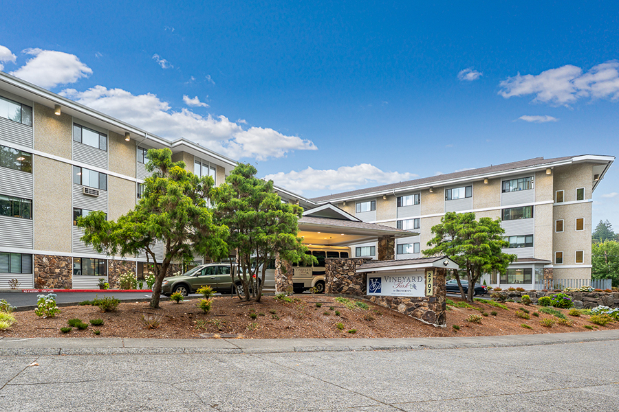 Modern hotel entrance with landscaping and blue sky.