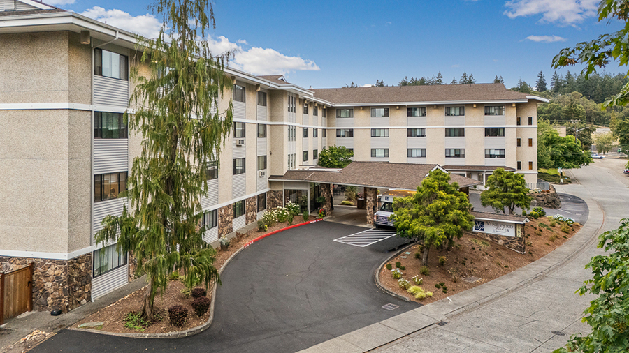 Multi-story building with driveway and green landscaping.