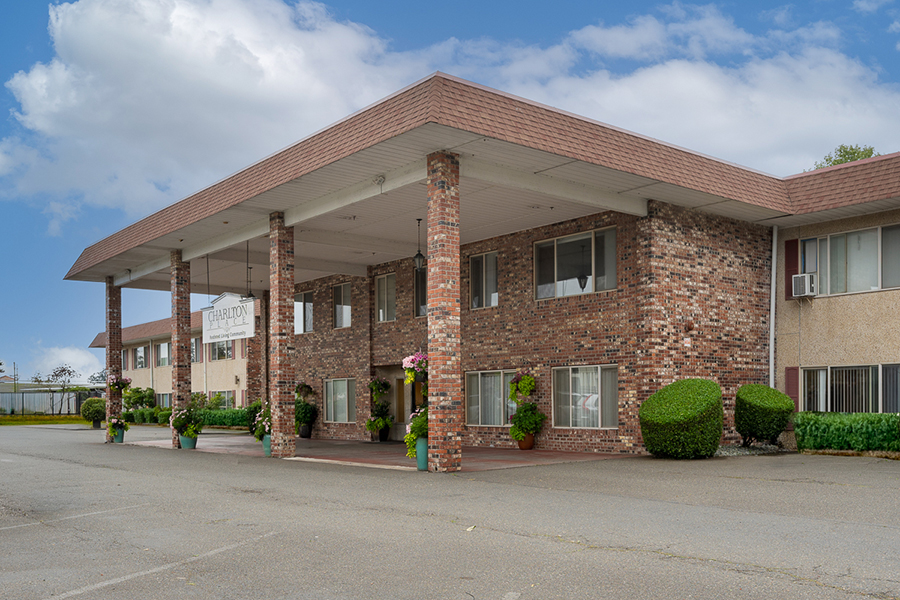 Brick building with a covered entrance and greenery.