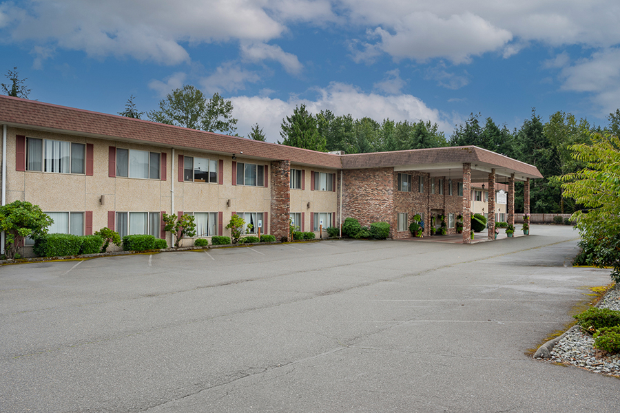 Motel exterior with trees and cloudy sky background.