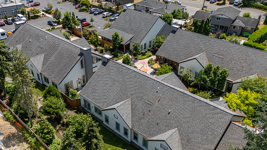 Aerial view of residential buildings with greenery and parking.