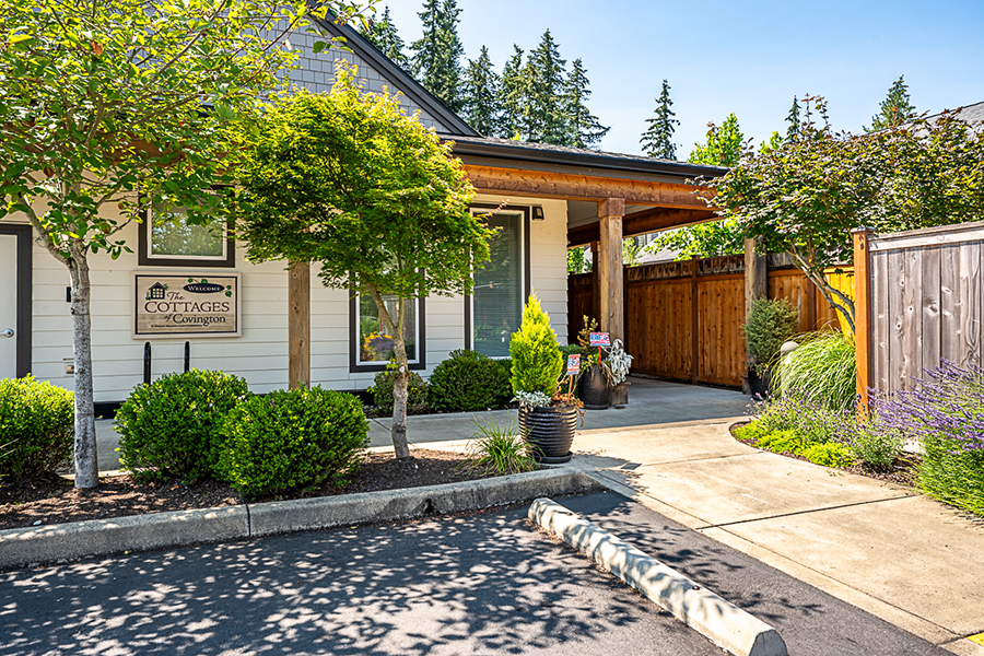 Charming cottage entrance with lush greenery and signage.