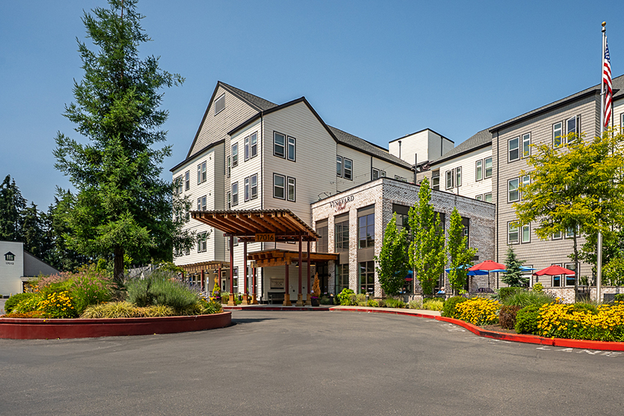 Modern hotel entrance with landscaped surroundings and clear sky.