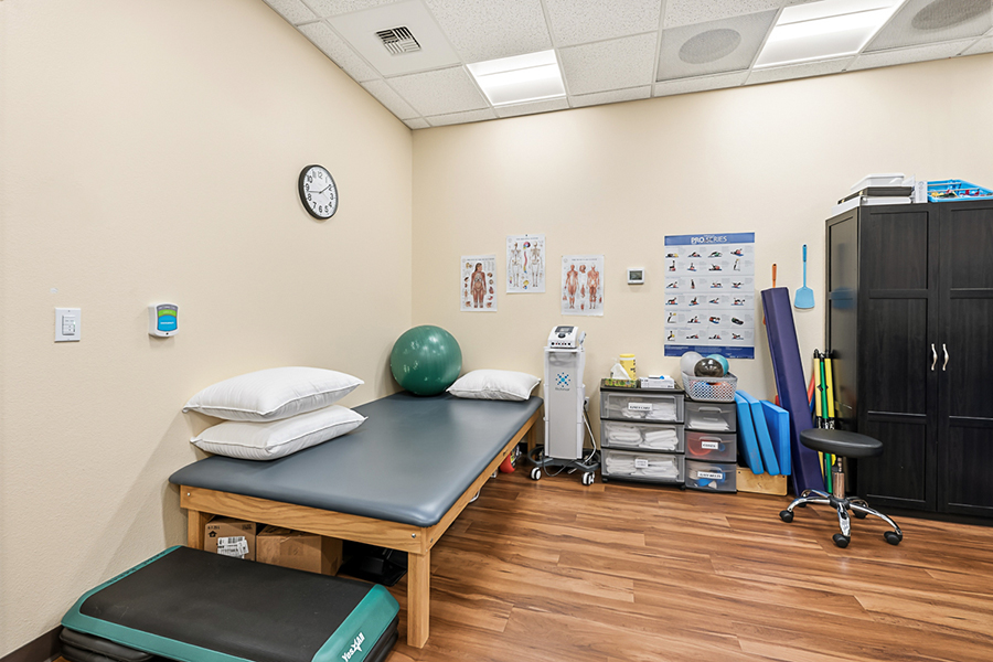 Physical therapy room with equipment and bedding.