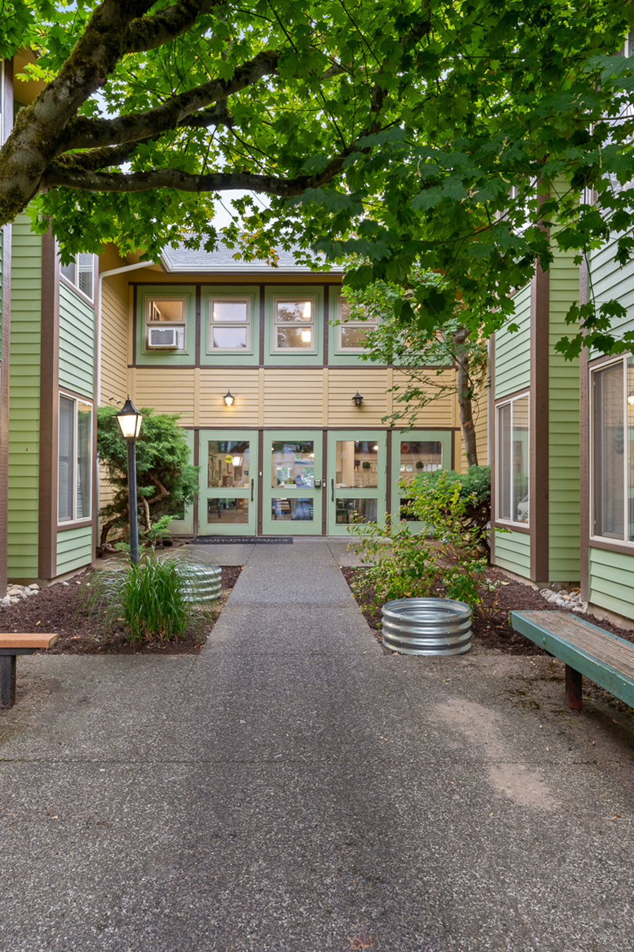 Pathway leading to a green and beige multi-story building.