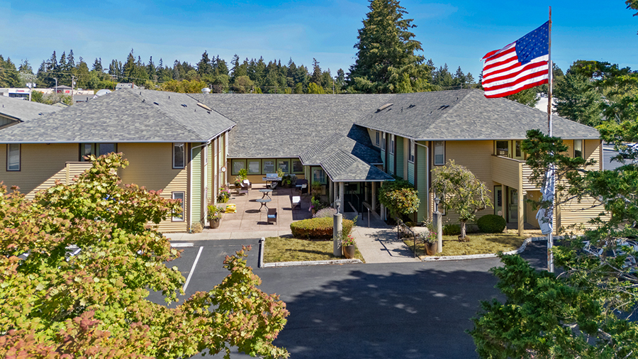 Modern building with American flag and landscaped surroundings.
