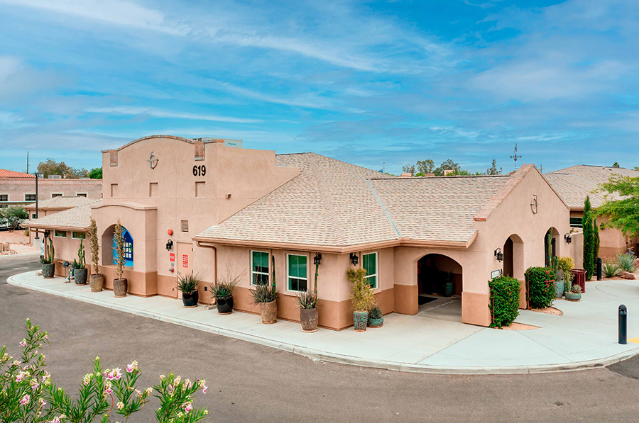 Single-story adobe-style building with landscaping and blue sky.