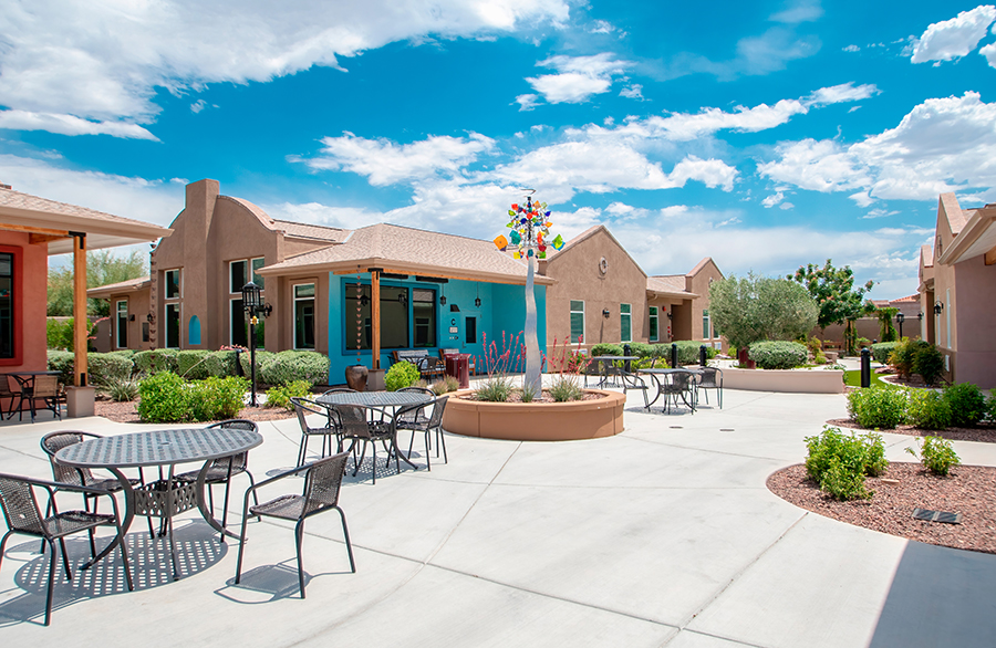 Colorful courtyard with seating, plants, and clear blue sky.