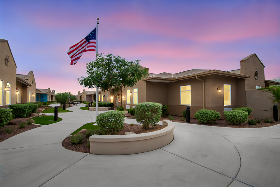 Residential courtyard with American flag and colorful sky.