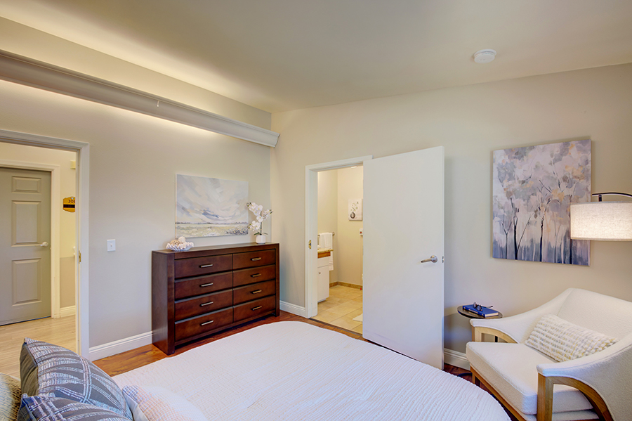 Cozy bedroom with dresser, artwork, and accessible bathroom.
