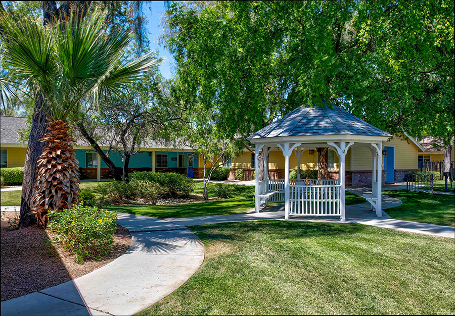 Lush green garden with gazebo and colorful cottages.