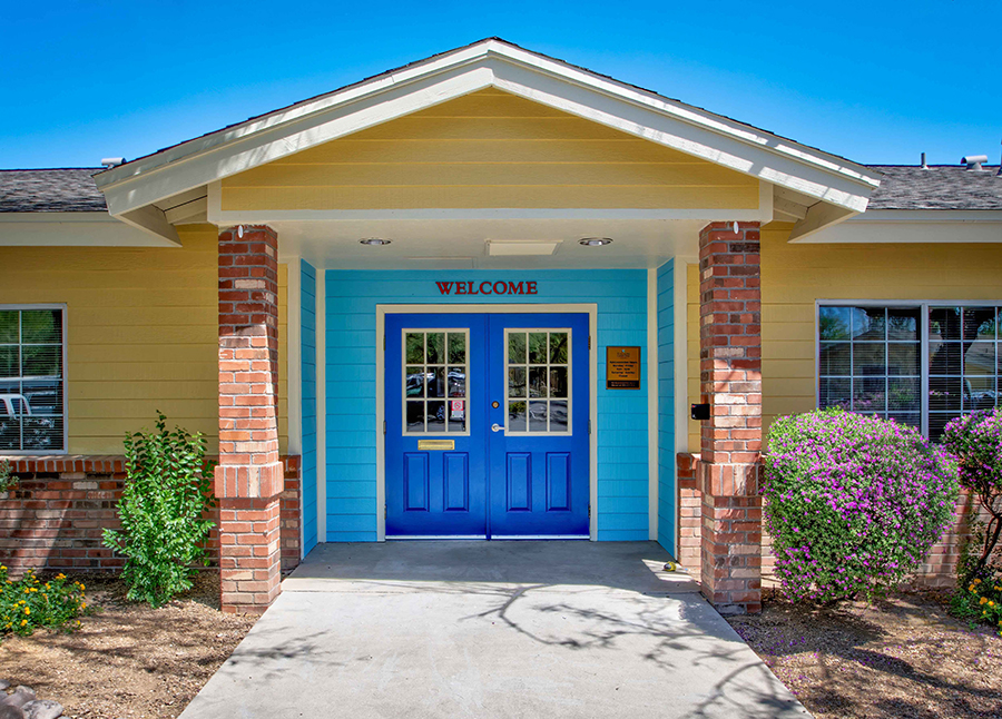 Colorful building entrance with "WELCOME" sign and greenery.