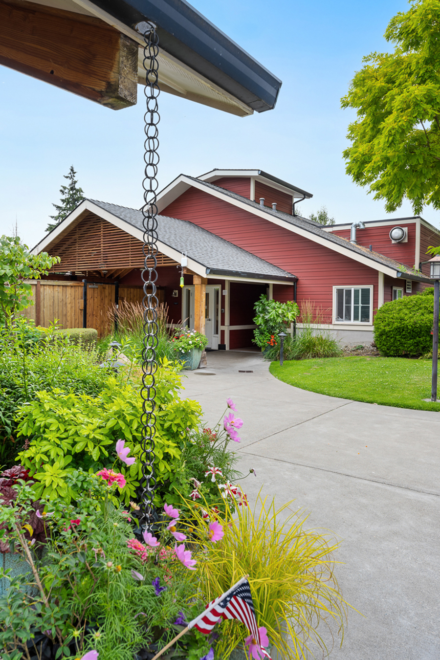 Charming red house with lush garden and pathway.
