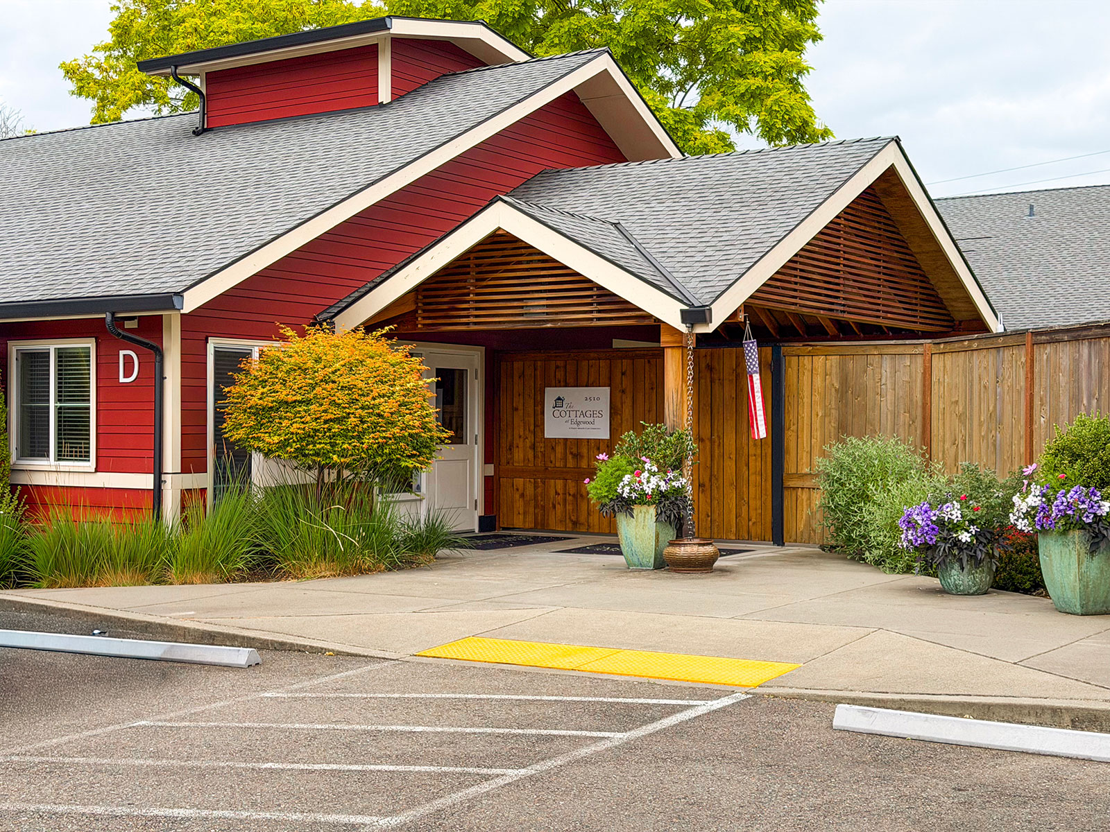 Red building entrance with landscaping and flowers.