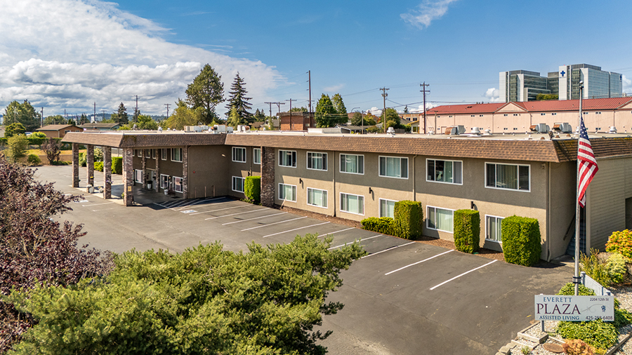 Two-story building with parking and greenery nearby.