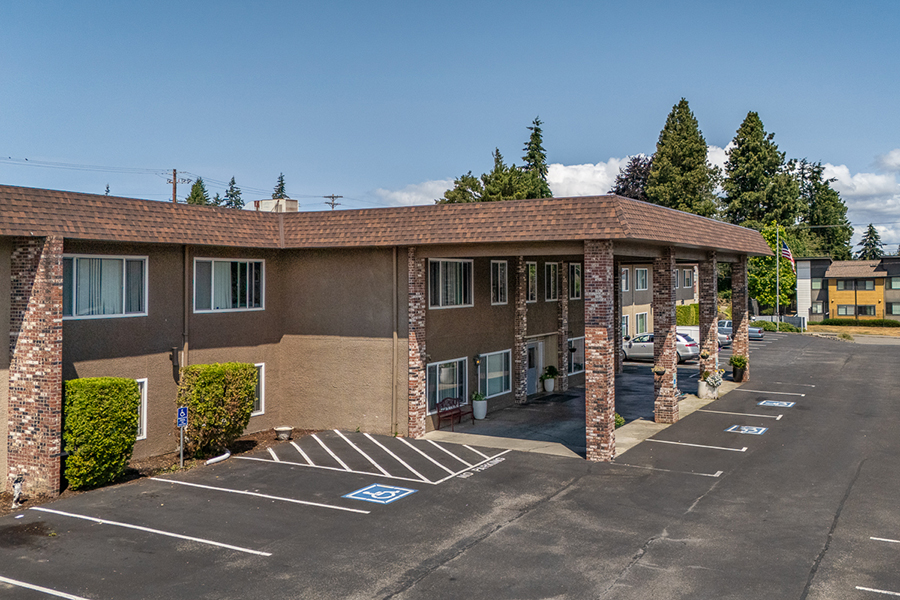 Two-story motel with parking and greenery.
