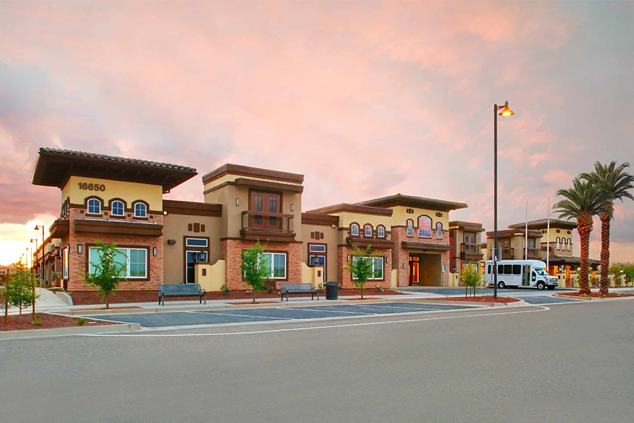 Elegant building exterior with palm trees and colorful sky.