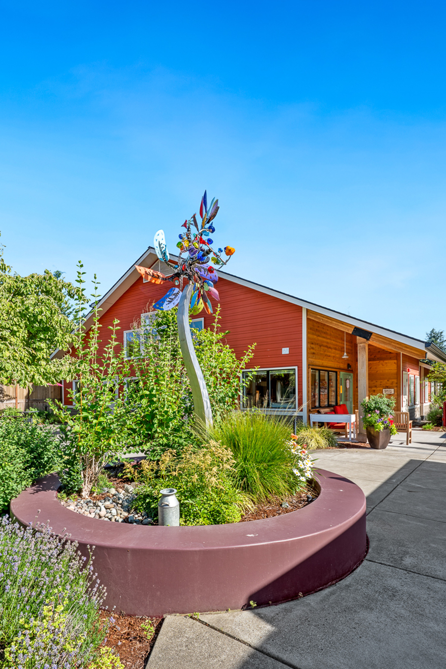 Colorful garden sculpture near a modern, red house.