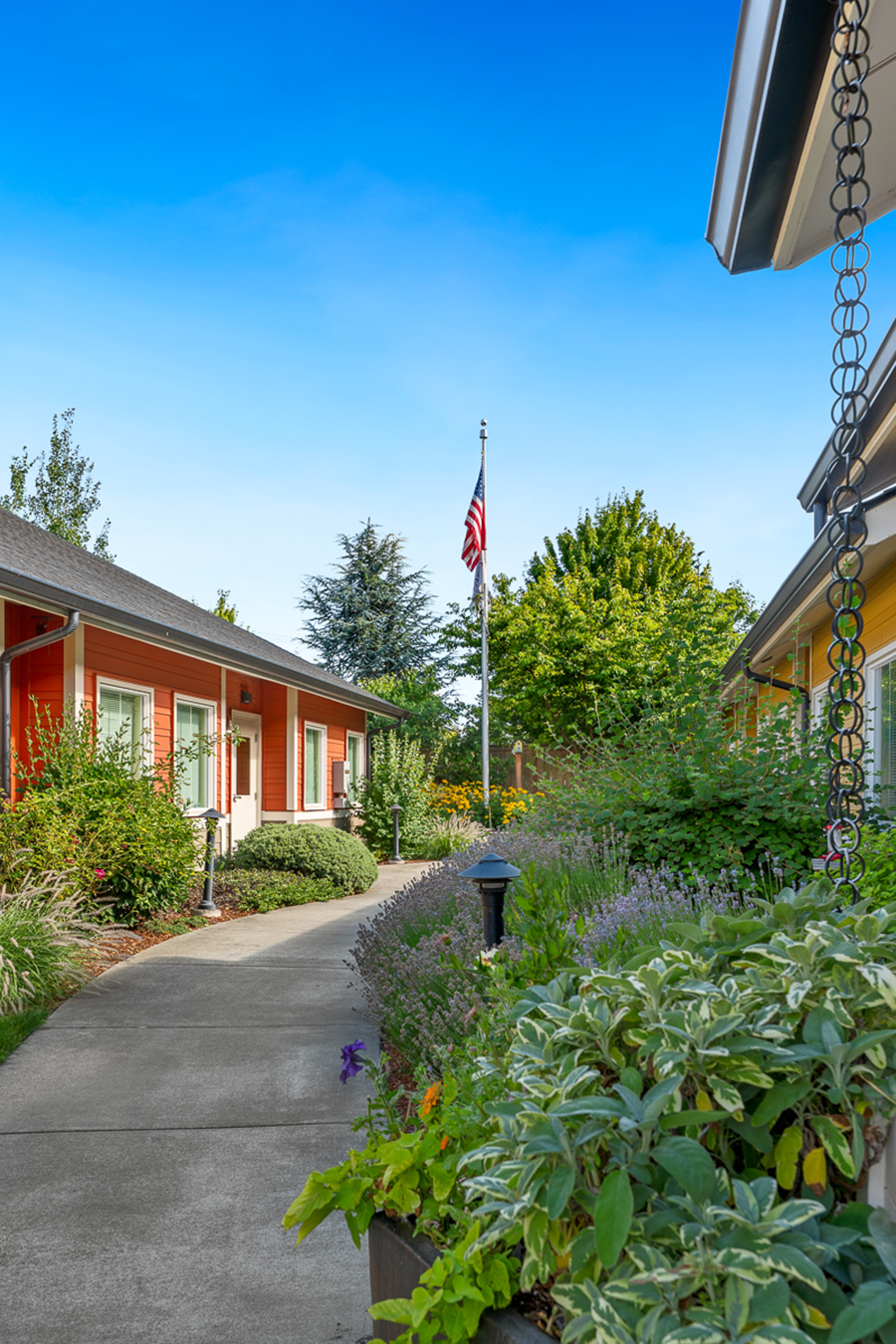 Colorful houses with garden path and American flag visible.