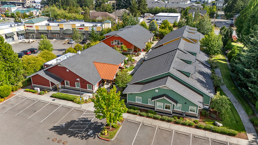 Multi-colored buildings in a landscaped parking area.