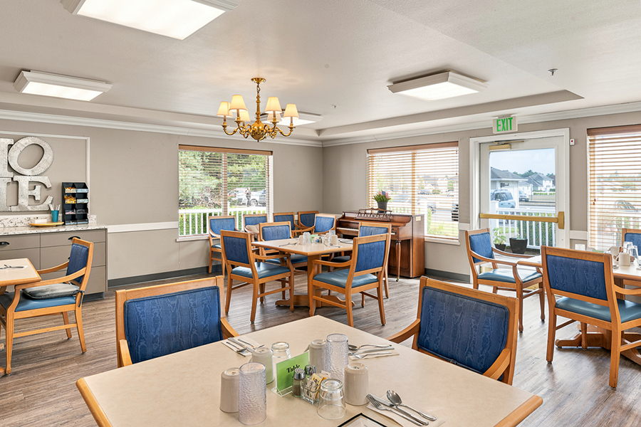 Bright dining area with wooden tables and blue chairs.