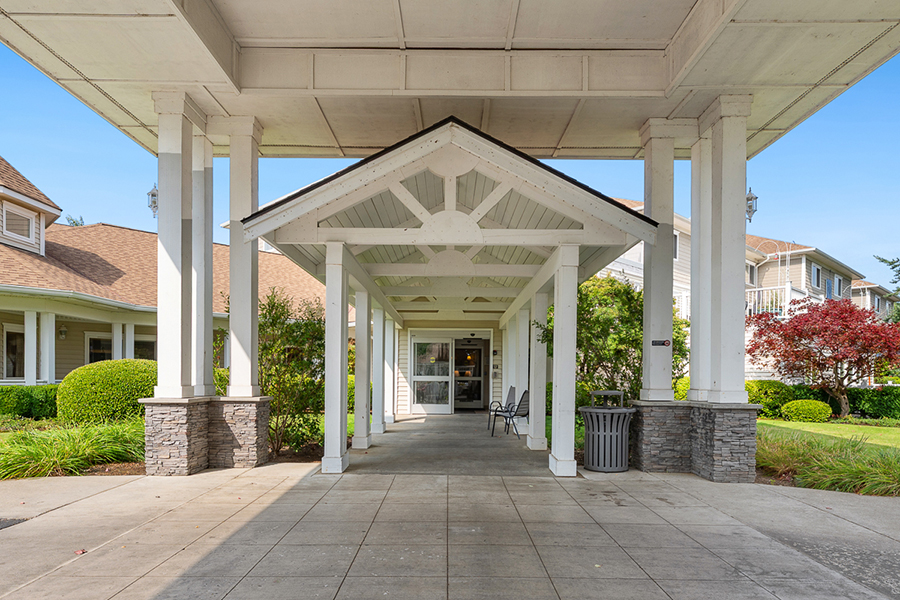 Welcoming entrance with a roof and pillars, surrounded by greenery.