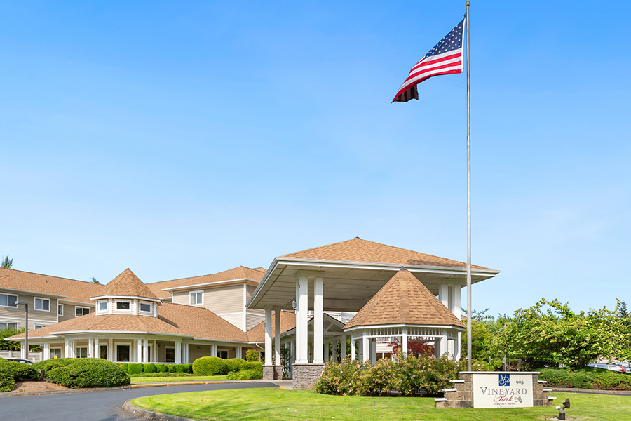 Building entrance with a flag and landscaped surroundings.